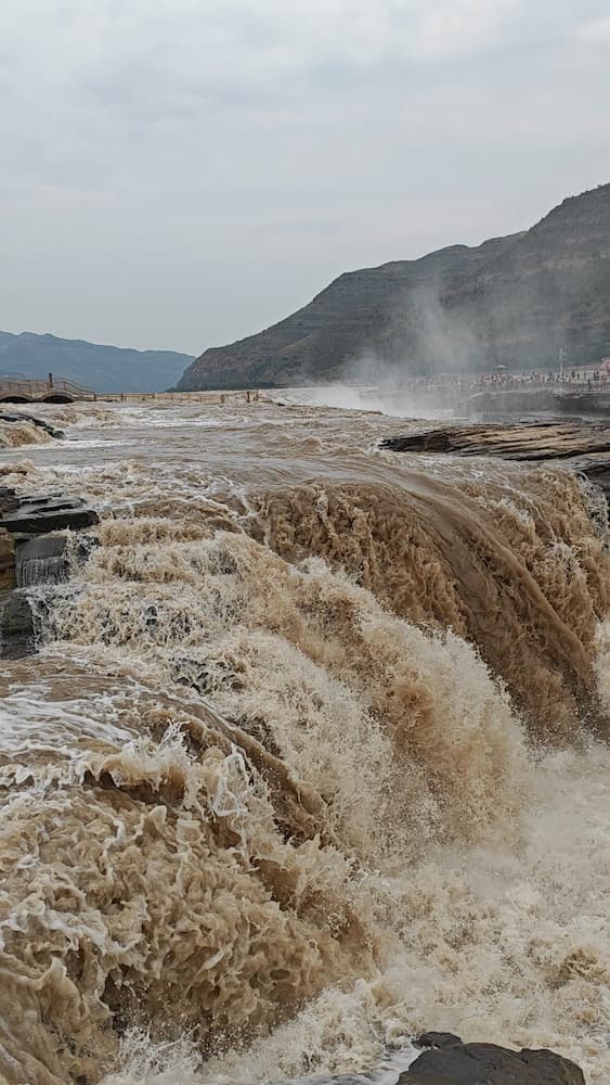 Golden sunset over Hukou Waterfall, China—powerful Yellow River rapids with mist rainbows.
